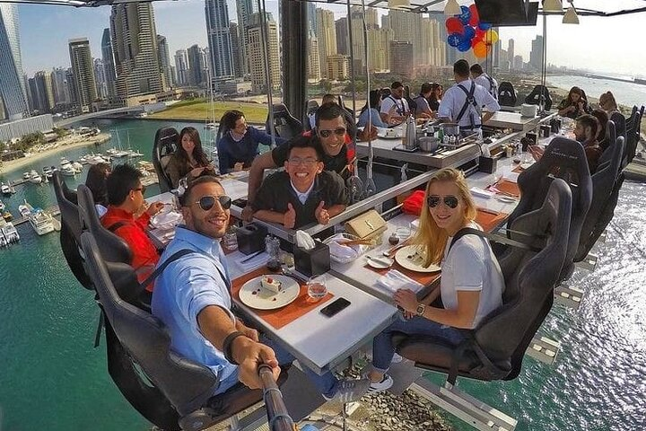 Dine 50 meters above Dubai's stunning skyline indulging in gourmet flavors while capturing unforgettable moments with friends in this unique culinary adventure suspended in the air.